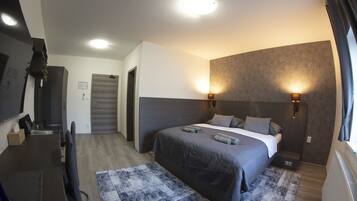 A modern bedroom with a bed, bedside lamps, a desk, and a patterned rug.