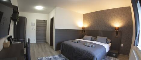 Un dormitorio moderno con cama, lámparas de noche, escritorio y alfombra estampada.
