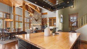 A spacious kitchen with a large island, wooden beams, stone accents, and a stone fireplace. - Gorgeous Private Home with Breathtaking Views of Red and Buffalo Mountain! (Silverthorne)