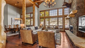 A spacious living room with wooden floors, a stone fireplace, and a mounted deer head. - Gorgeous Private Home with Breathtaking Views of Red and Buffalo Mountain! (Silverthorne)
