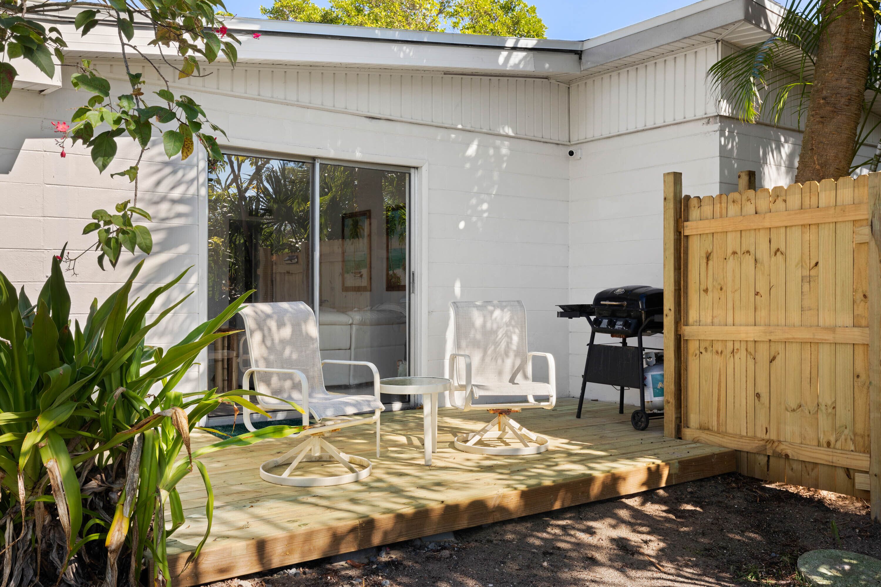Un patio con mesa y sillas, una parrilla y una valla de madera.