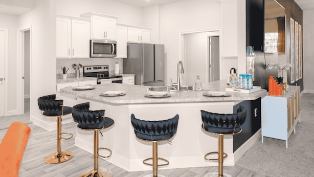 A modern kitchen with white cabinets, stainless steel appliances, and a central island with bar stools. - Palm Bay Retreat: Pool, Amenities & Free Parking
 (Palm Bay)