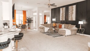 A modern living room with a sectional sofa, a coffee table, and a dining area with chairs and a table. - Palm Bay Retreat: Pool, Amenities & Free Parking
 (Palm Bay)