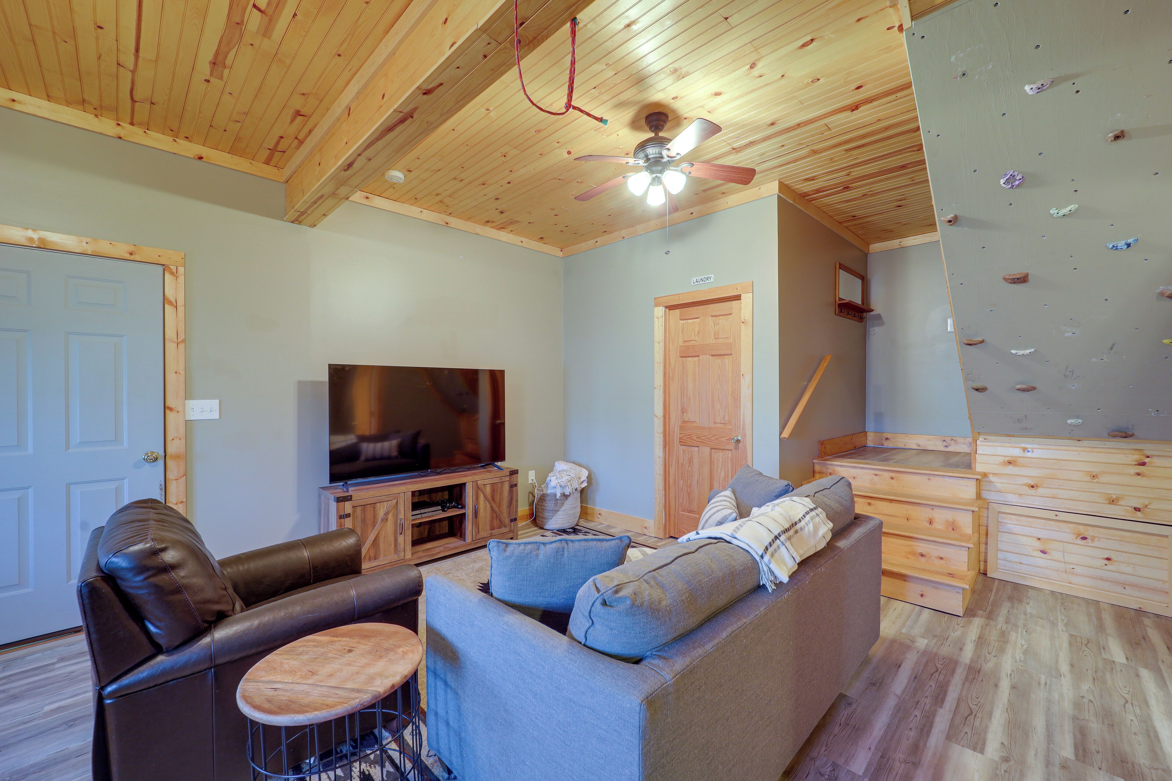 A living room with a sofa, a television, and a climbing wall.