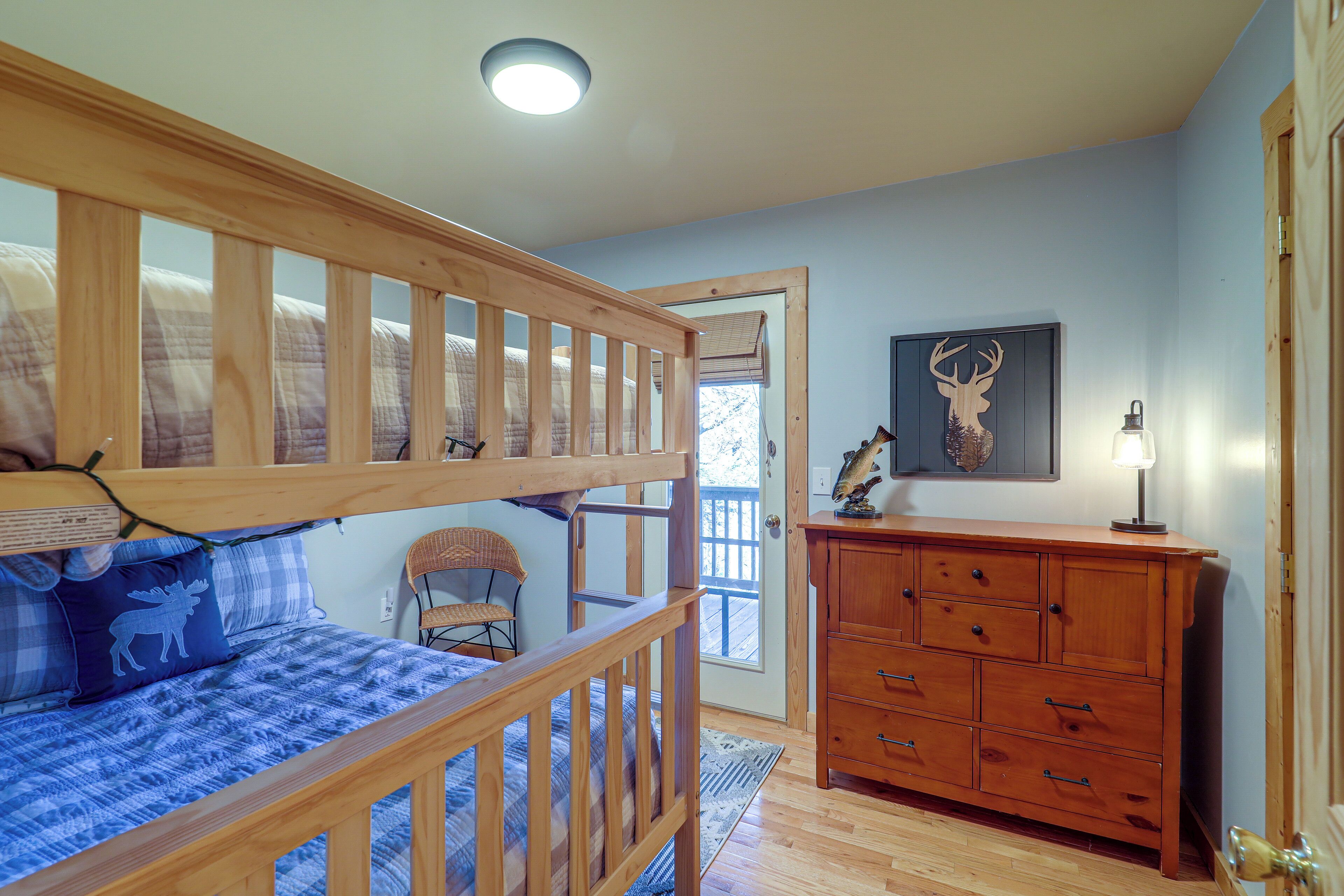 Une chambre avec un lit superposé, une commode, une chaise et une porte donnant sur l’extérieur.
