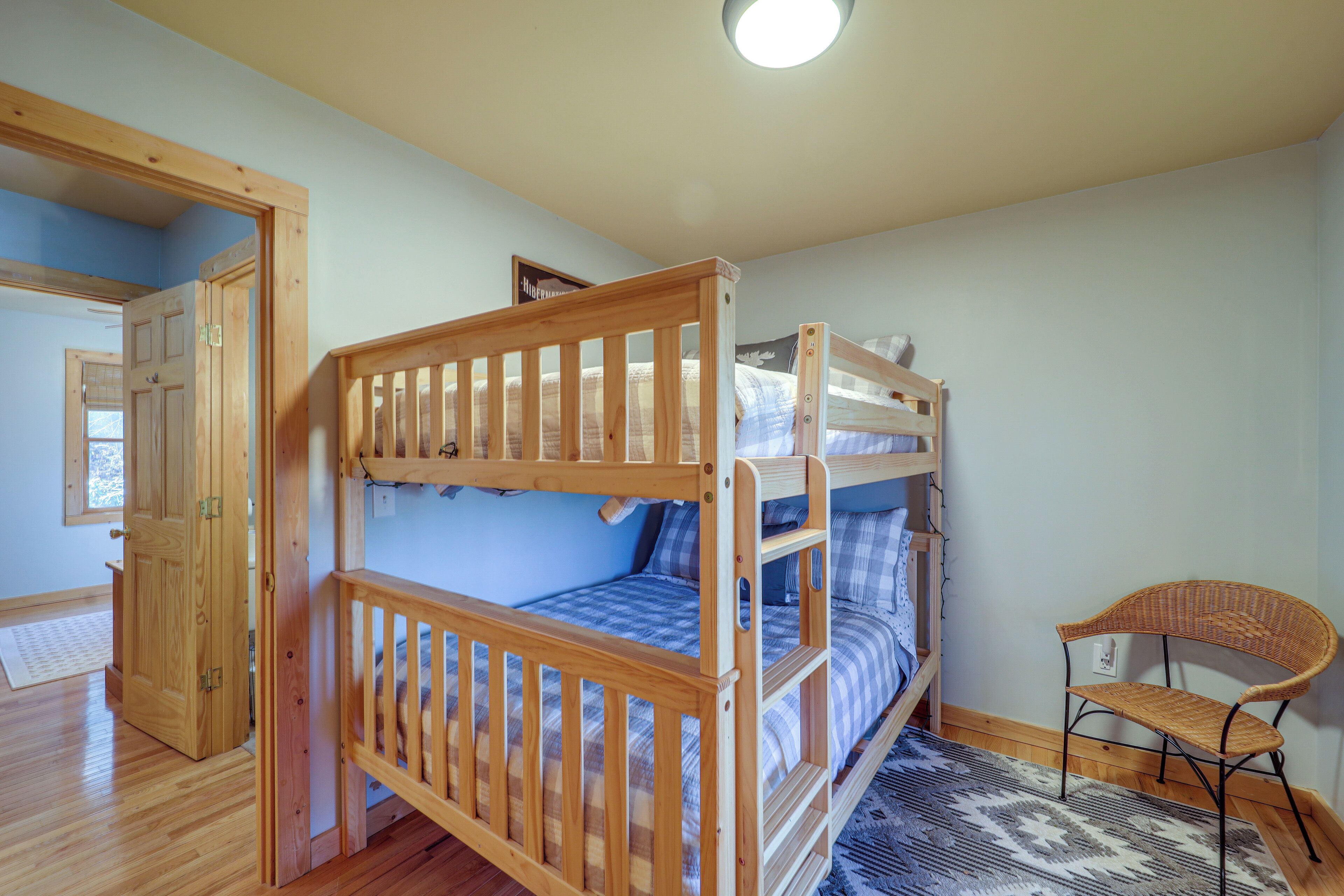 A room with a bunk bed, a wooden chair, and a door leading to another room.