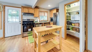 A modern kitchen with wooden cabinets, a stainless steel refrigerator, a built-in microwave, and a wooden dining table. - Salem Vacation Home w/ Dock: Steps to Paddock Lake (Salem)