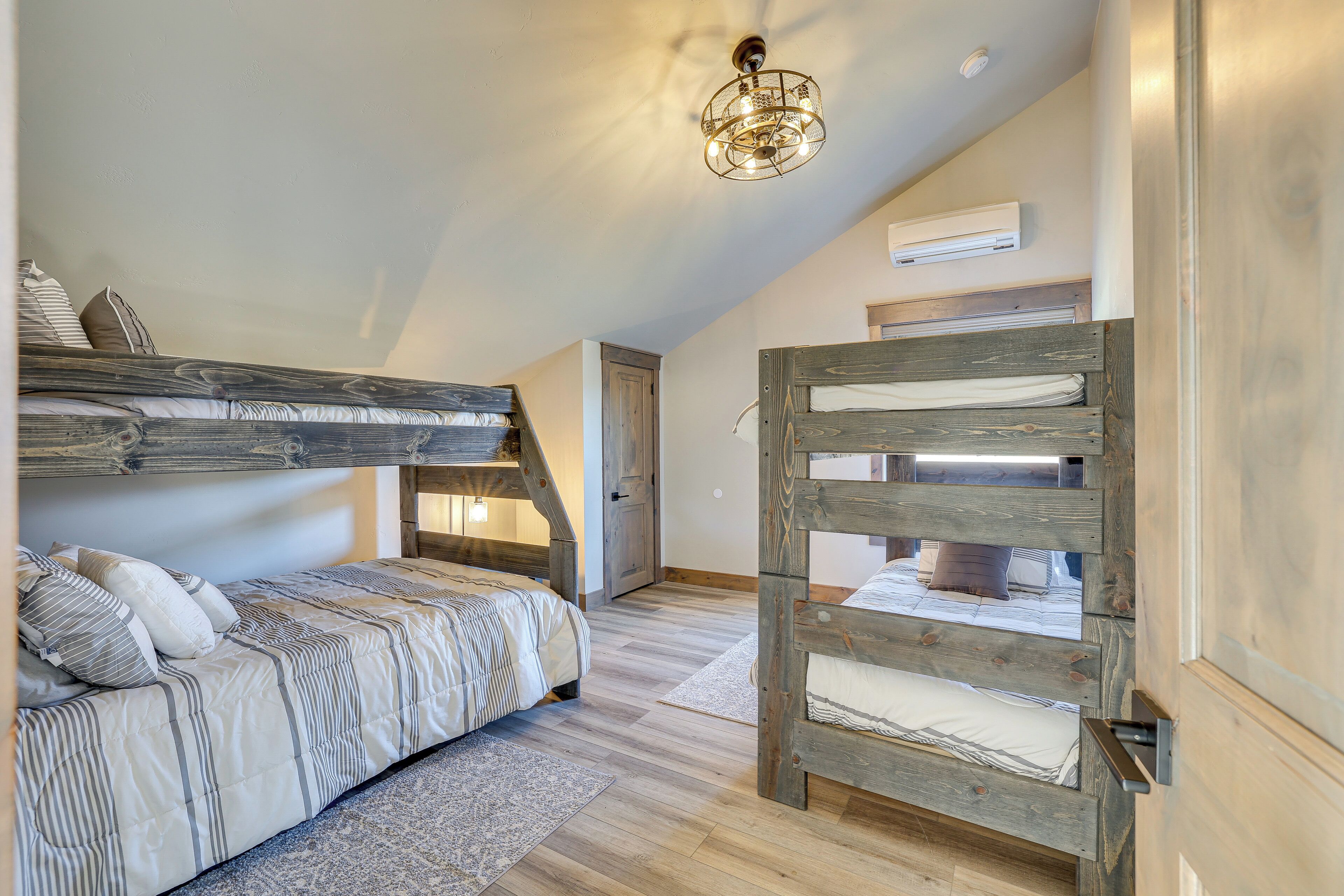 Dormitorio tipo loft con una cama litera, una escalera de madera y una lámpara en el techo.