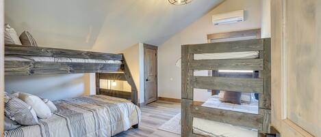 Dormitorio tipo loft con una cama litera, una escalera de madera y una lámpara en el techo.