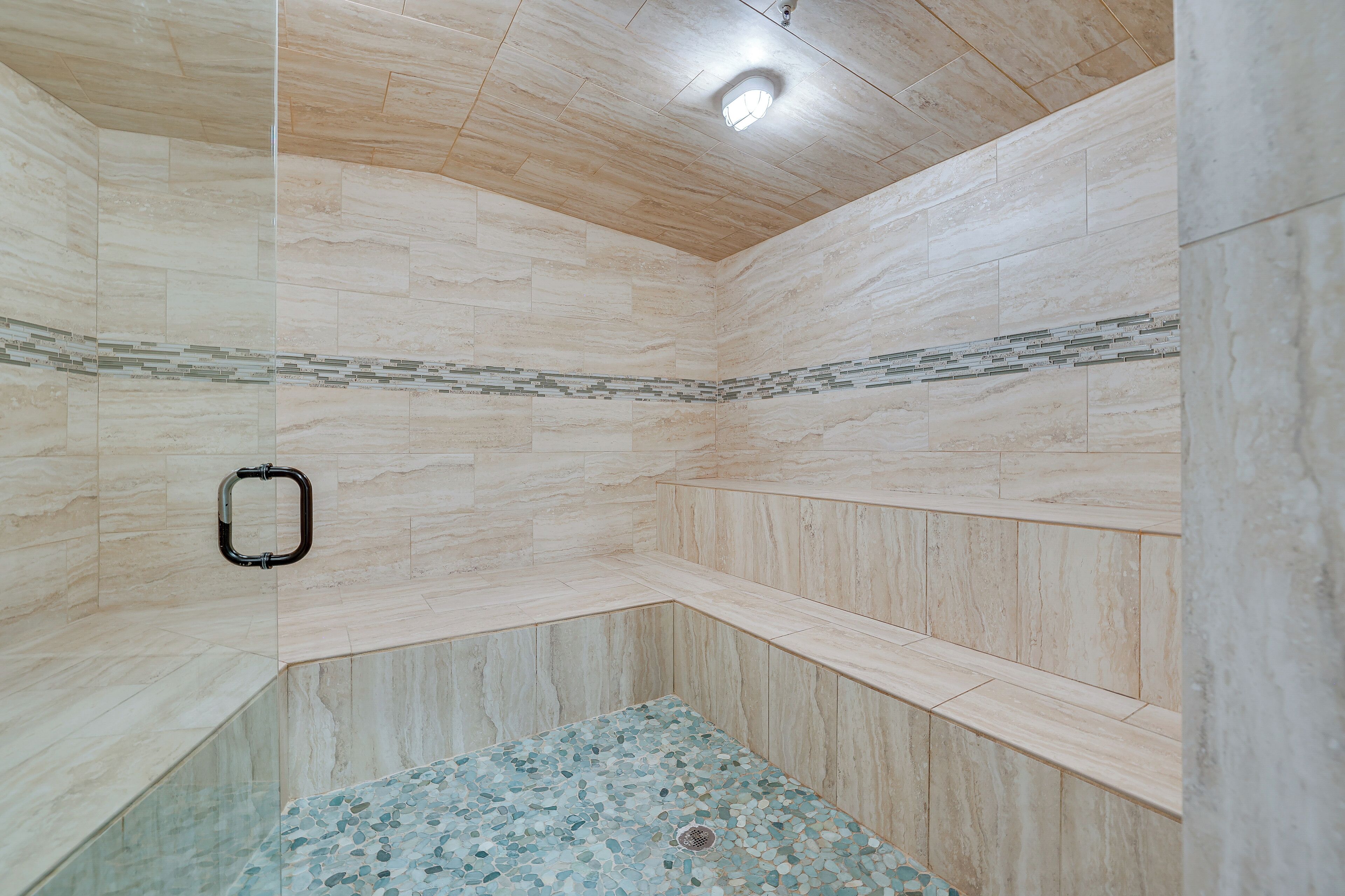 A shower with a tiled floor and a handrail.