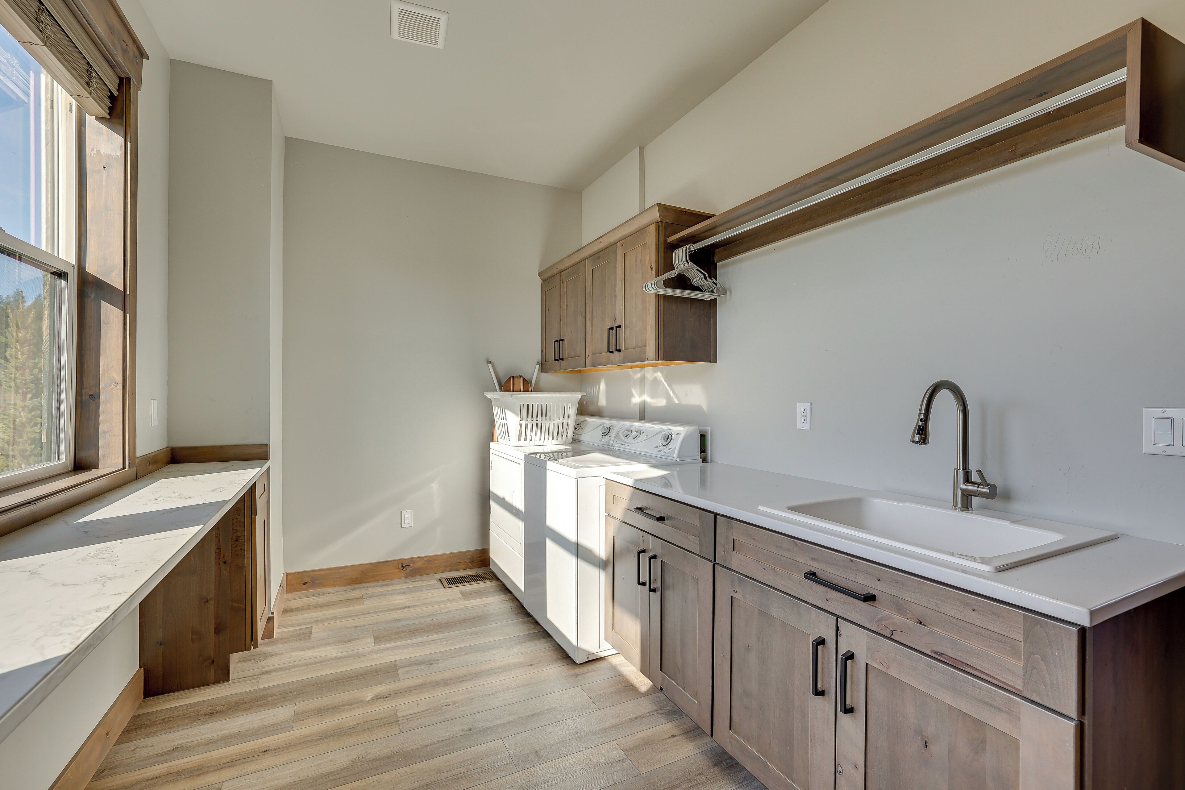 Una cocina moderna con lavadora y secadora integradas, armarios de madera y un ventanal que proporciona luz natural.
