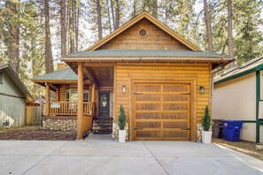 A log cabin with a porch, a stone foundation, and a garage. - Big Bear Lake Retreat w/ Game Room: 1 Mi to Slopes (Big Bear Lake)