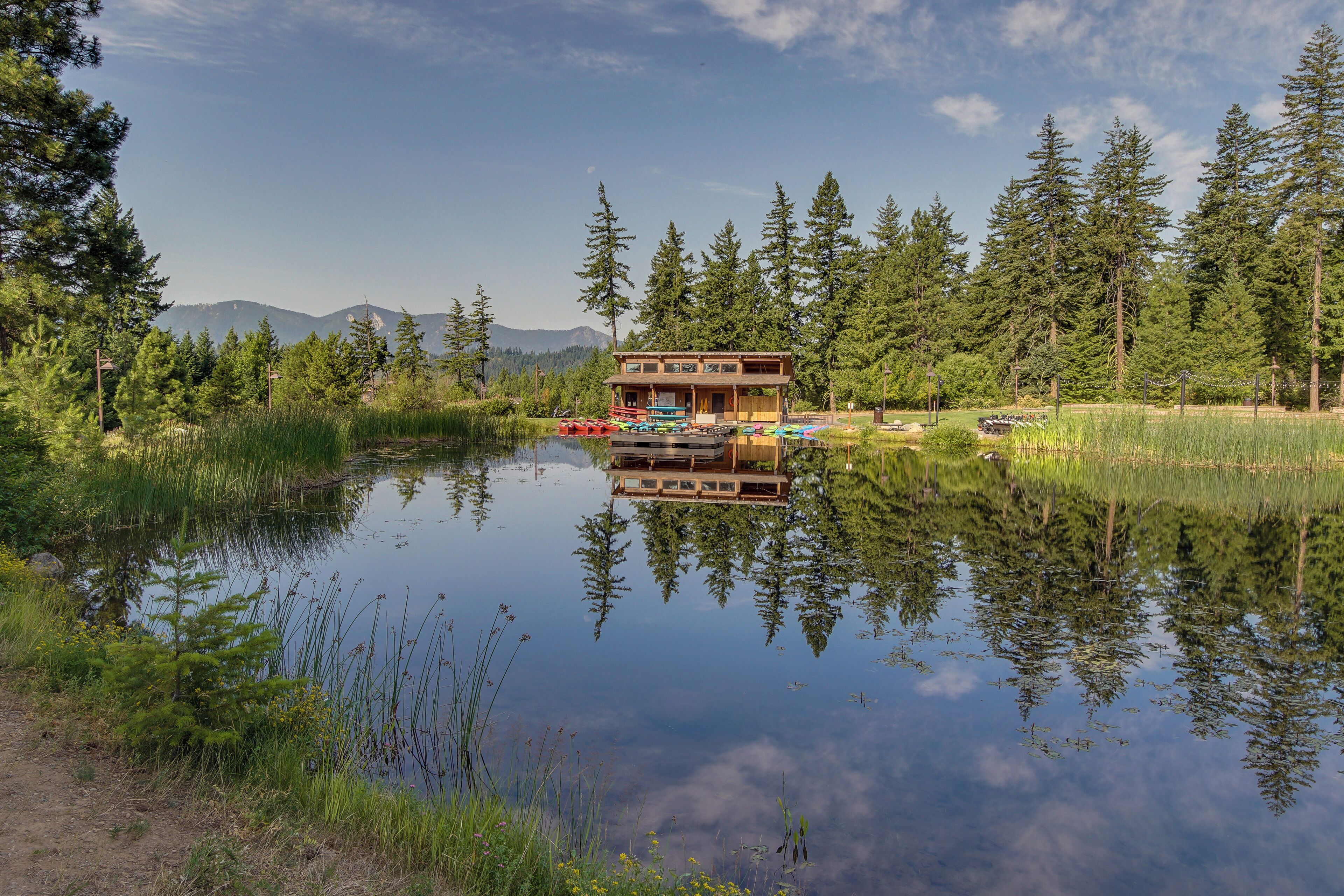 Una cabaña con un muelle, rodeada de un bosque y un lago.
