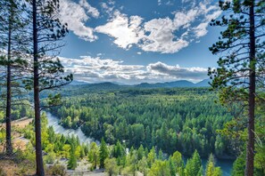 A forested landscape with a river and mountains in the distance. - Suncadia Resort Condo: Balcony & Golf Course Views (Cle Elum)