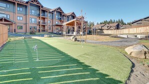 A residential complex with multiple apartment buildings, a well-maintained lawn, and a covered outdoor seating area. - Suncadia Resort Condo: Balcony & Golf Course Views (Cle Elum)