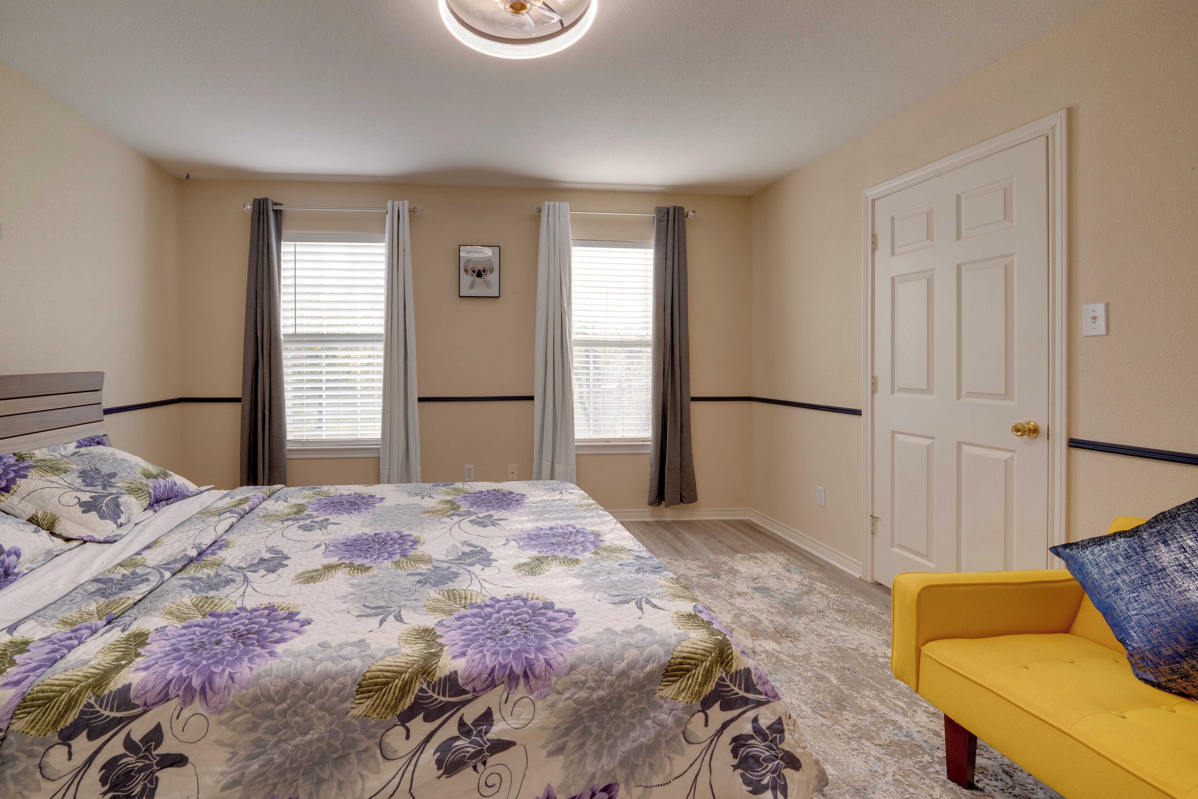A bedroom with a bed, a yellow chair, and a door.