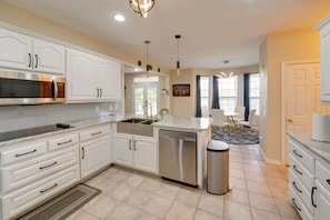 A modern kitchen with white cabinetry, stainless steel appliances, and a central island. - 13 Mi to Dtwn Mckinney! Family Getaway w/ Pool (Anna)