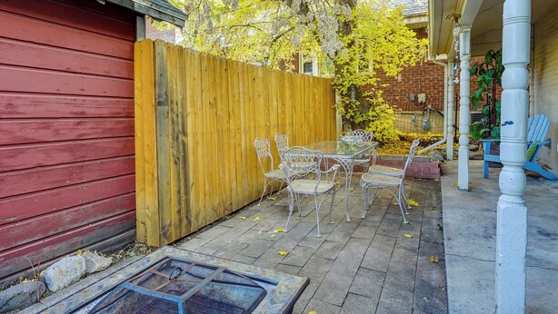 A patio area with a red building, a wooden fence, and outdoor furniture. - Charming Ogden Vacation Rental: 2 Mi to Downtown (Ogden)