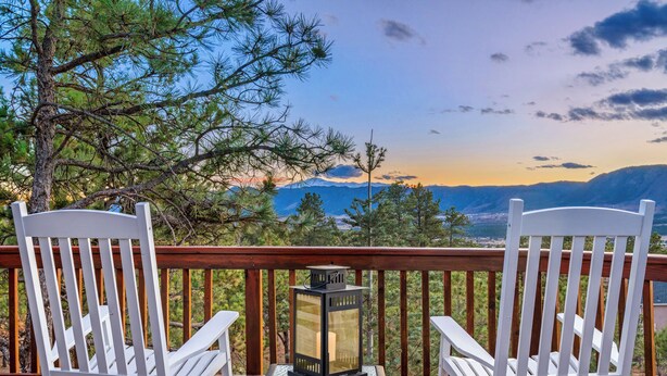 Two white Adirondack chairs on a wooden deck with a lantern table, overlooking a mountainous landscape. - Expansive Monument Home: Hot Tub & Mountain Views! (Monument)