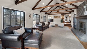 A spacious living room with leather sofas, a fireplace, and wooden beams on the ceiling. - Expansive Monument Home: Hot Tub & Mountain Views! (Monument)