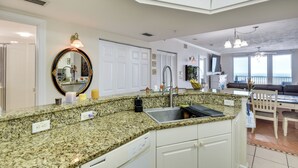 A kitchen with granite countertops, a sink, and a dining area with a table and chairs.