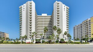 A multi-story hotel with a central atrium, surrounded by palm trees and a clear blue sky.