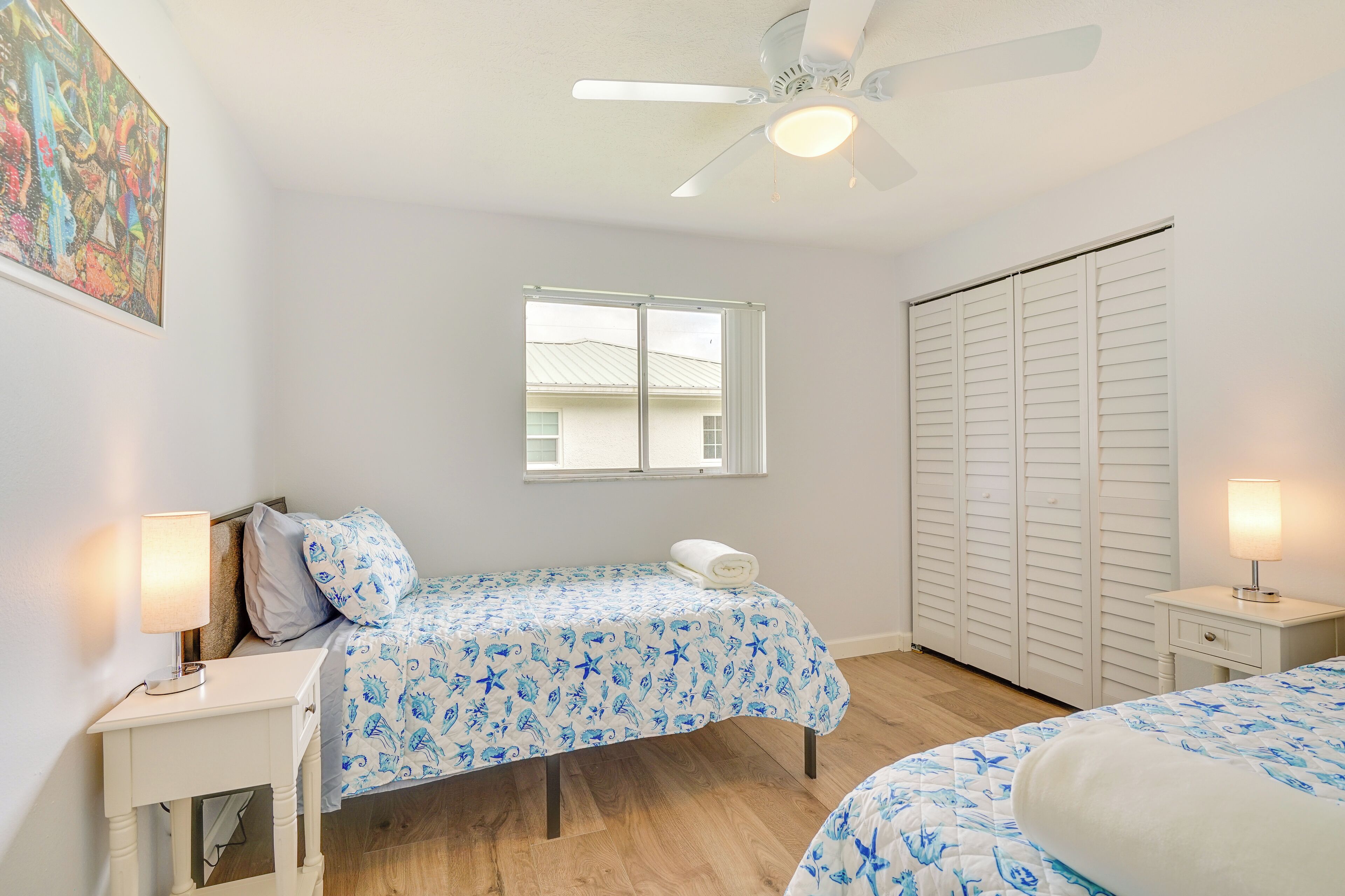 Ein Schlafzimmer mit zwei Betten, einem Deckenventilator, einem Fenster und einem Schrank.