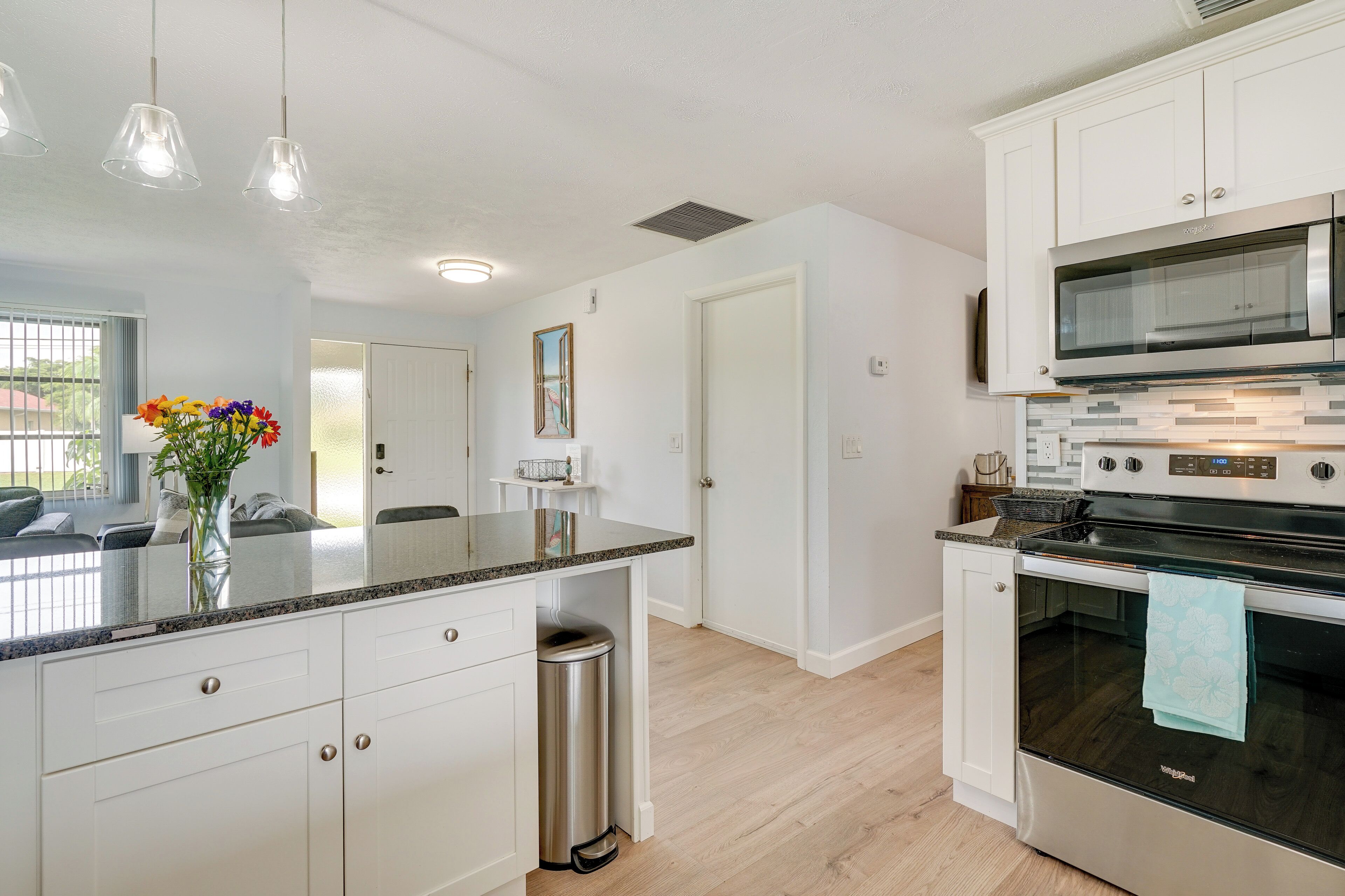 A modern kitchen with white cabinets, a stainless steel oven, and a granite countertop.