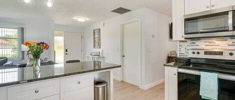 A modern kitchen with white cabinets, a stainless steel oven, and a granite countertop.