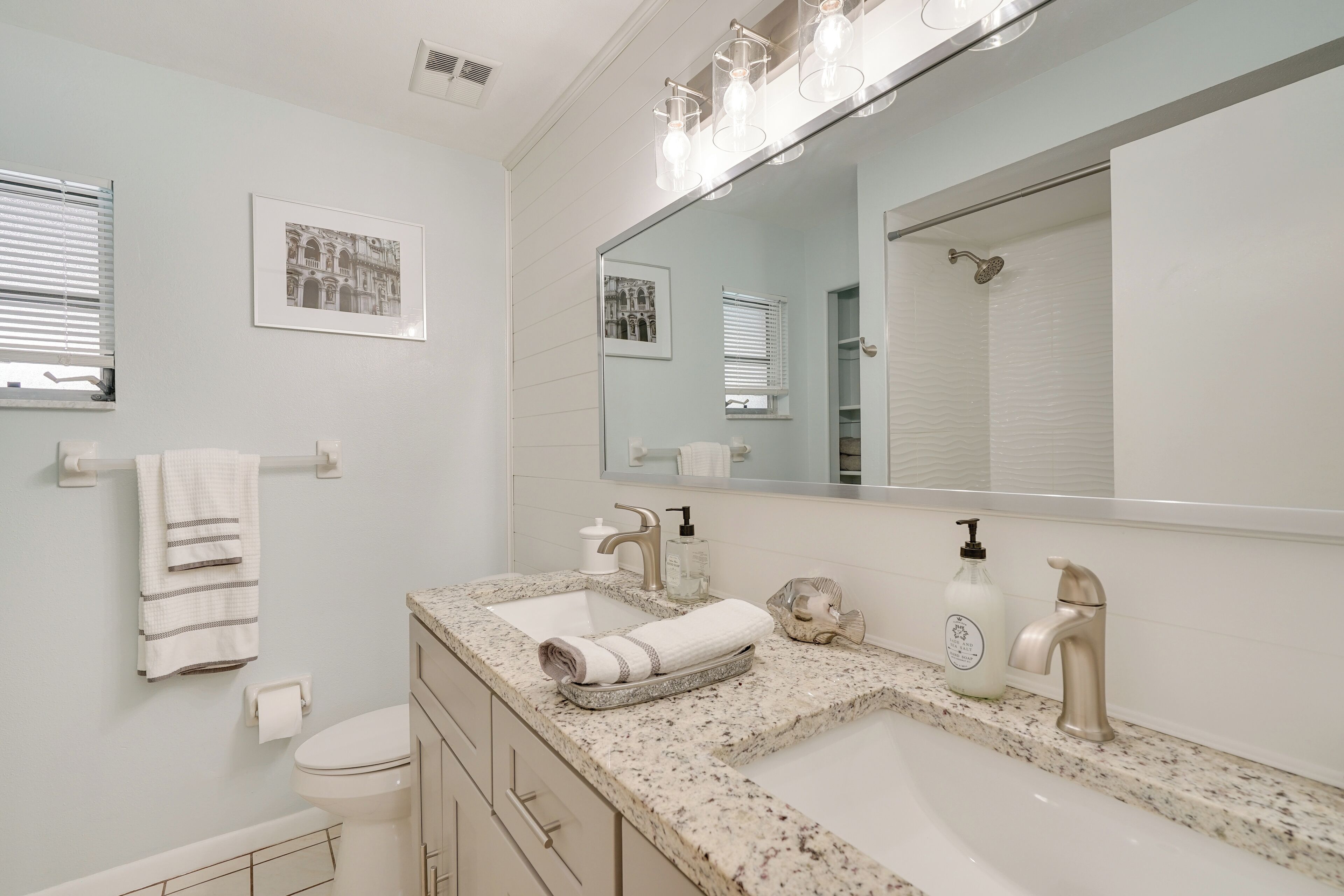 A bathroom with a double sink, a large mirror, and a towel rack.