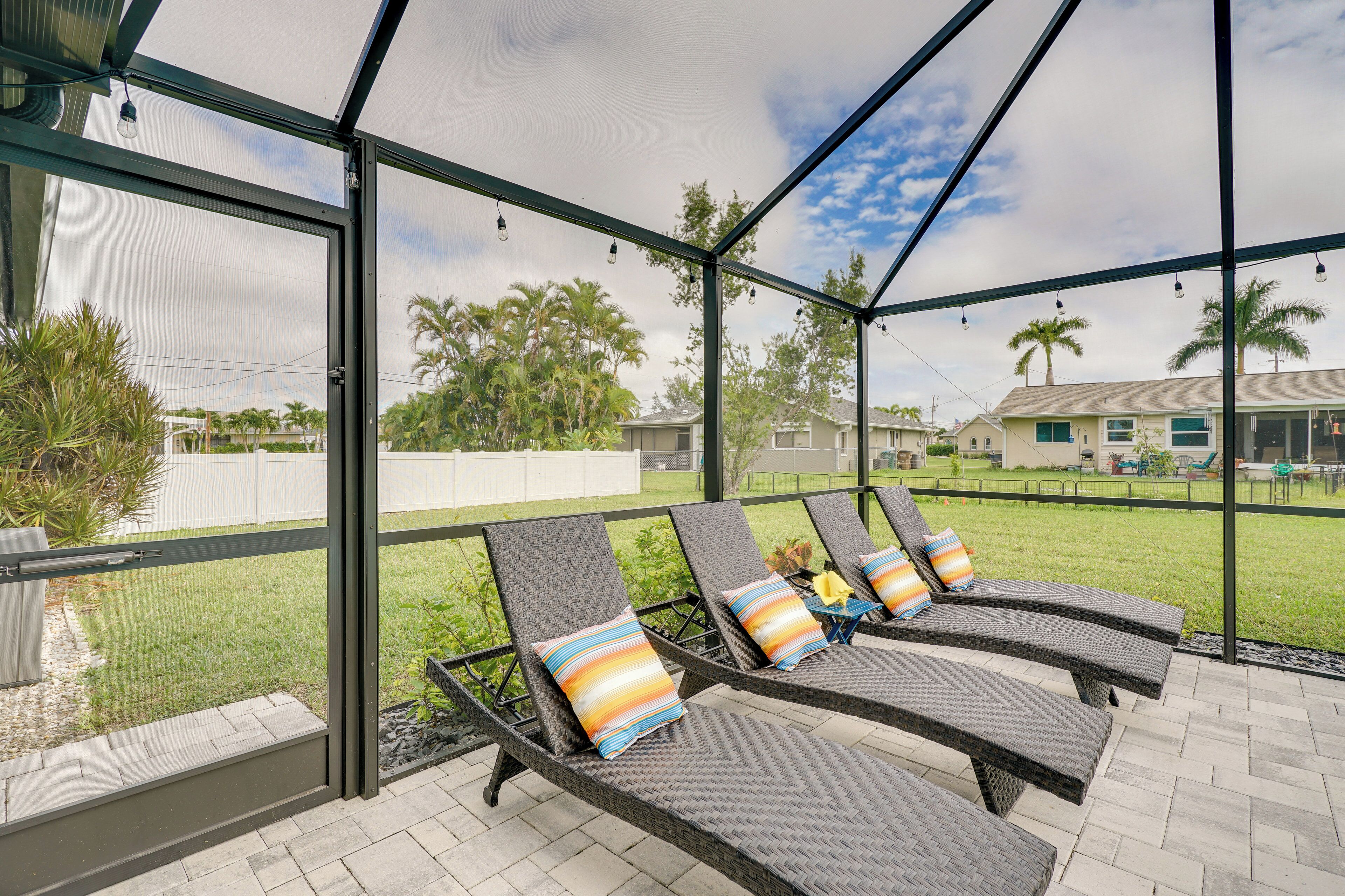 A covered outdoor seating area with wicker lounge chairs and colorful cushions.