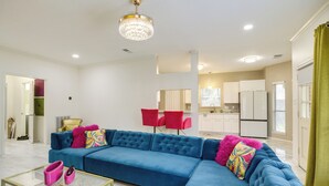 Ein modernes Wohnzimmer mit einem blauen Ecksofa, einem Glastisch und einer Deckenleuchte.