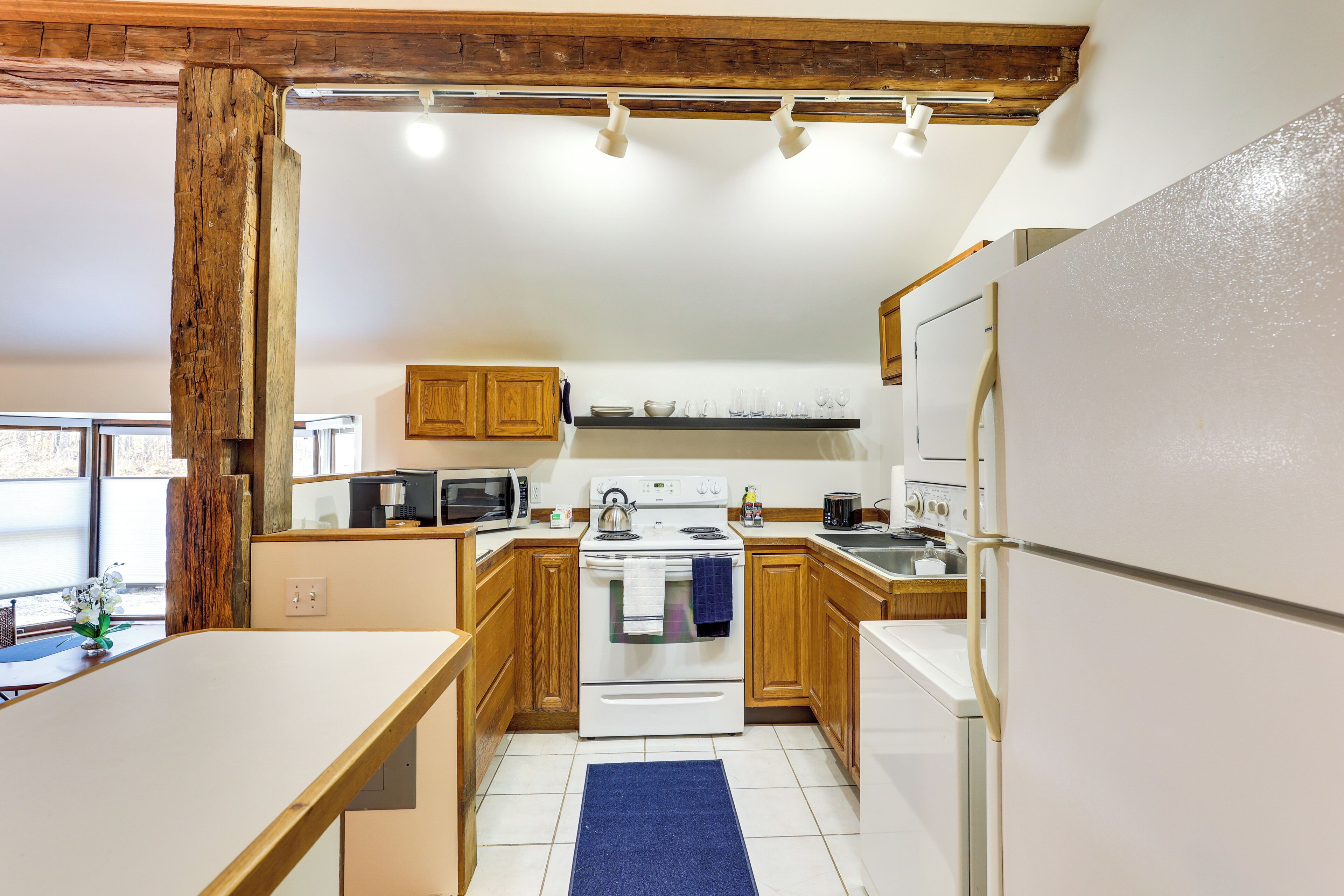 A kitchen with wooden cabinets, a white stove, a microwave, and a refrigerator.