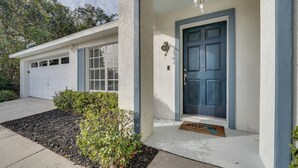 Une maison avec une porte bleue, un garage et un paillasson.