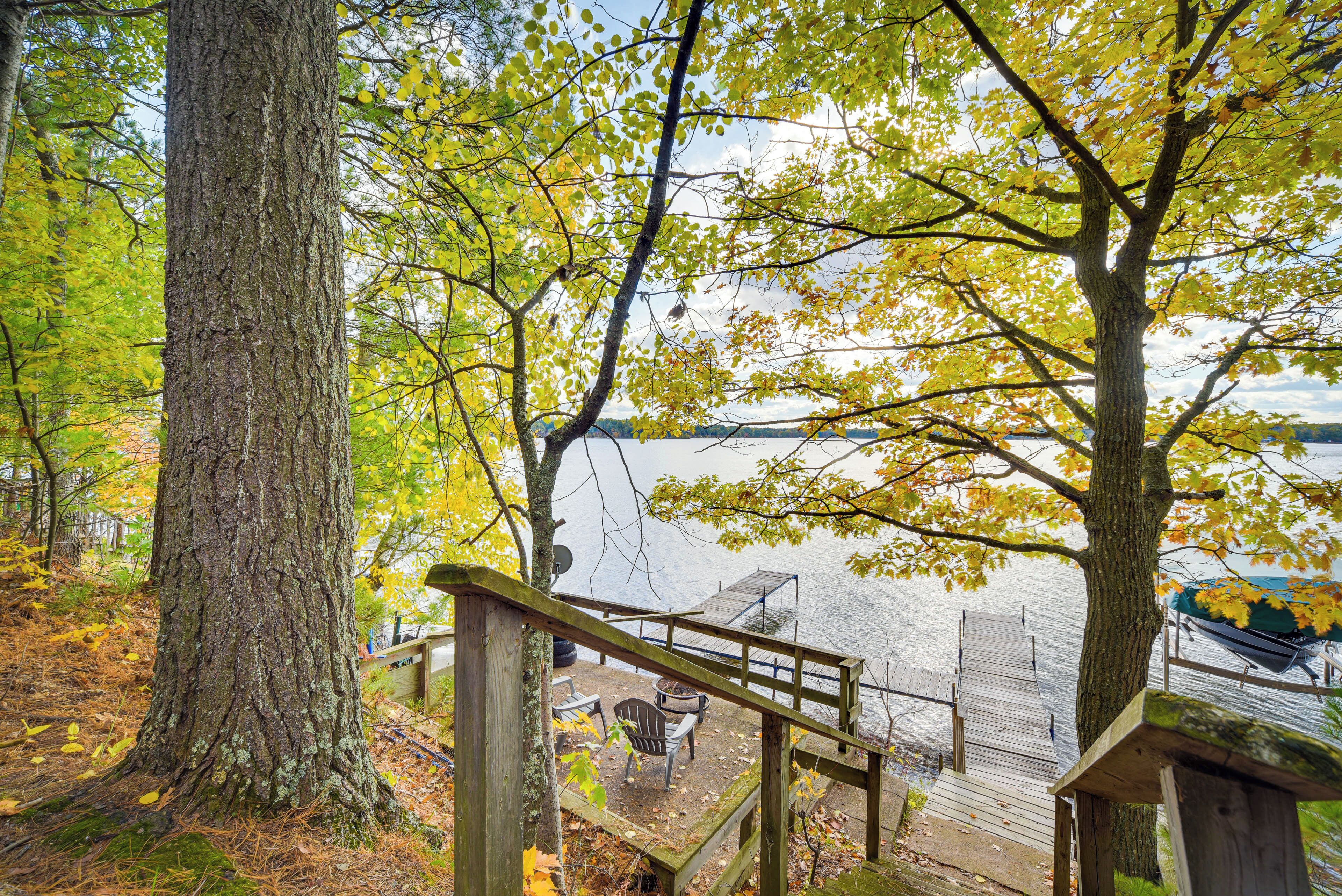 A wooden deck with a bench and a table overlooking a lake.