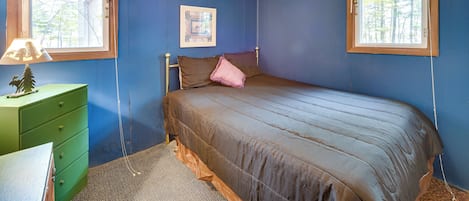 A bedroom with a bed, a dresser, and two windows.