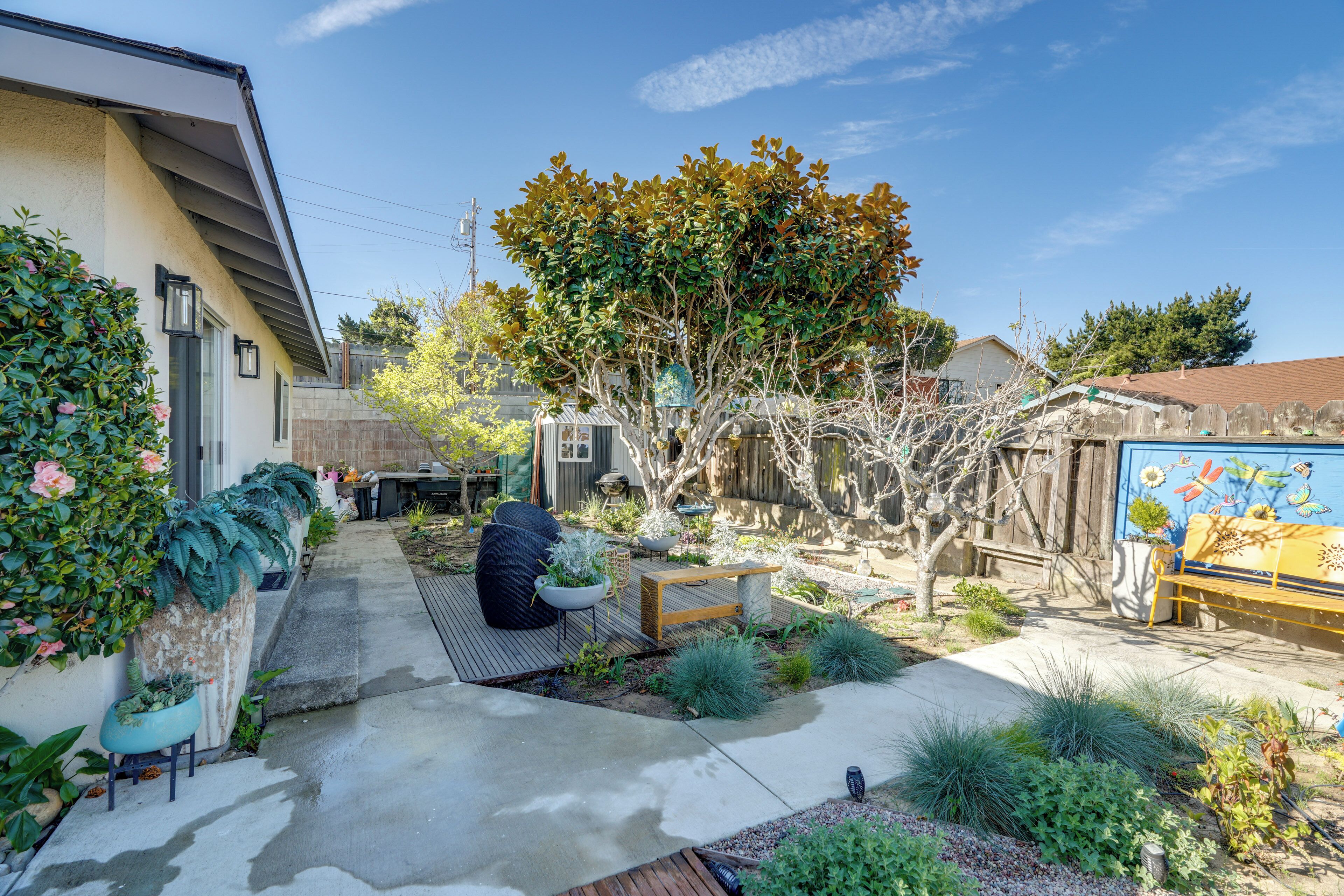 A residential backyard with a patio, seating area, and a mural on the wall.