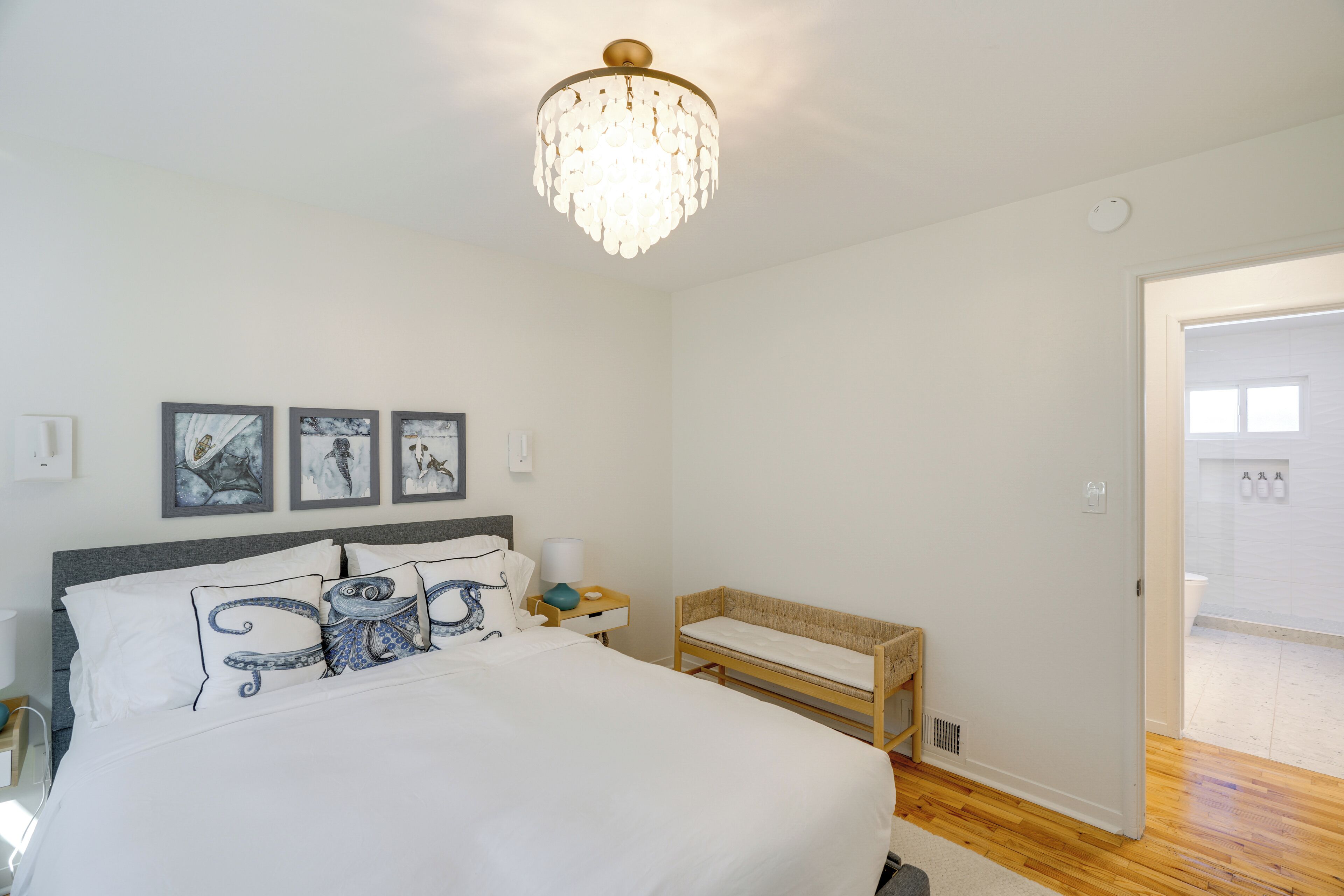 Une chambre à coucher avec un lit, une table de chevet, un banc et un lustre.