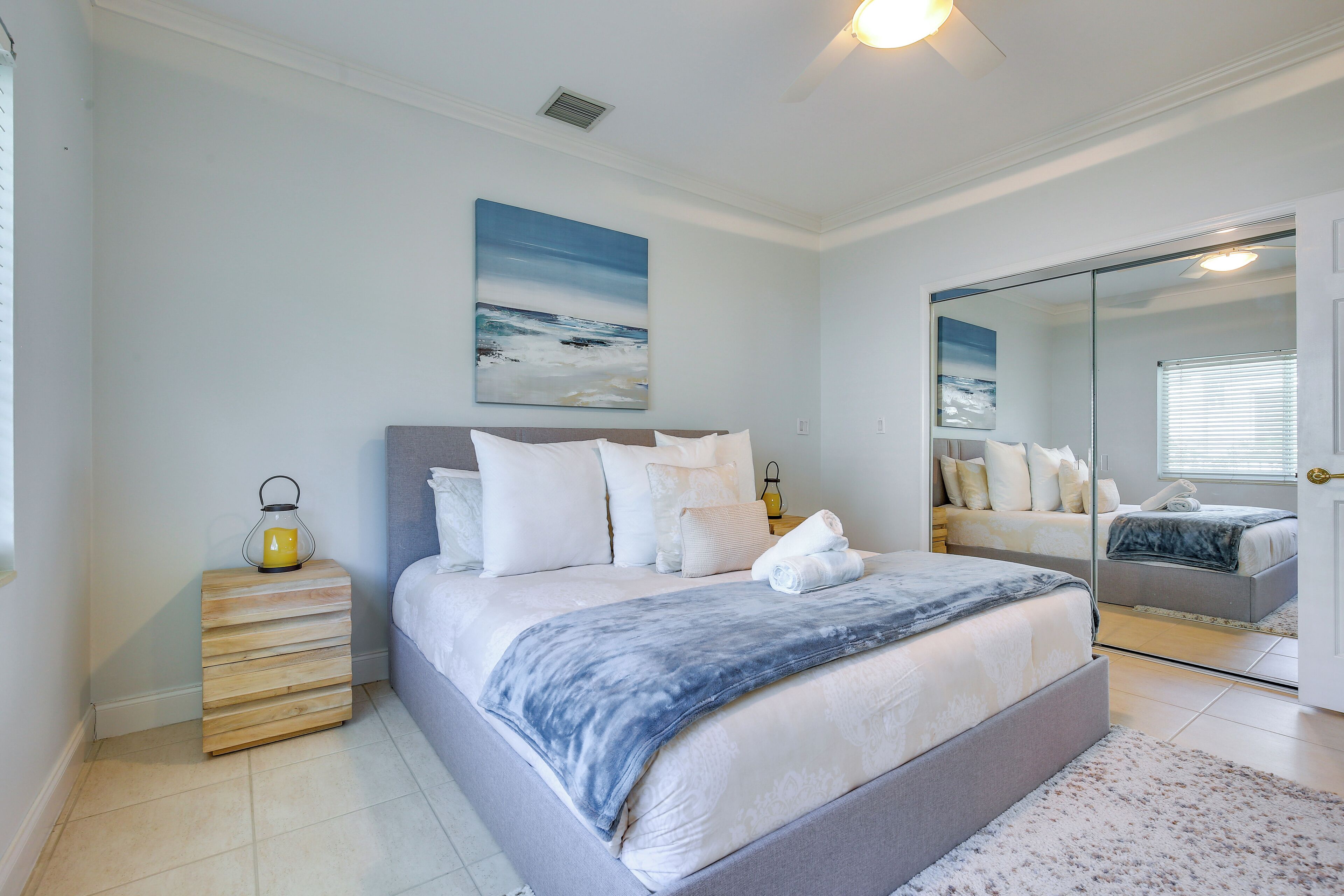 A bedroom with a bed, bedside table, and a large mirror.