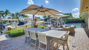 A patio area with outdoor seating, a pool, and boats. - Canal Access & Pool: Lighthouse Point Getaway! (Pompano Beach)