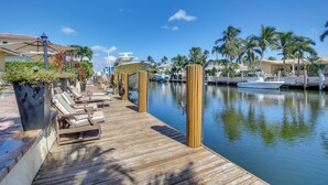 A wooden dock with lounge chairs, a marina with boats, and palm trees. - Canal Access & Pool: Lighthouse Point Getaway! (Pompano Beach)