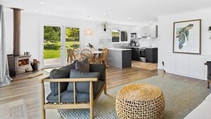 Un intérieur moderne comprenant un canapé, un coin repas, une cuisine et de grandes fenêtres.