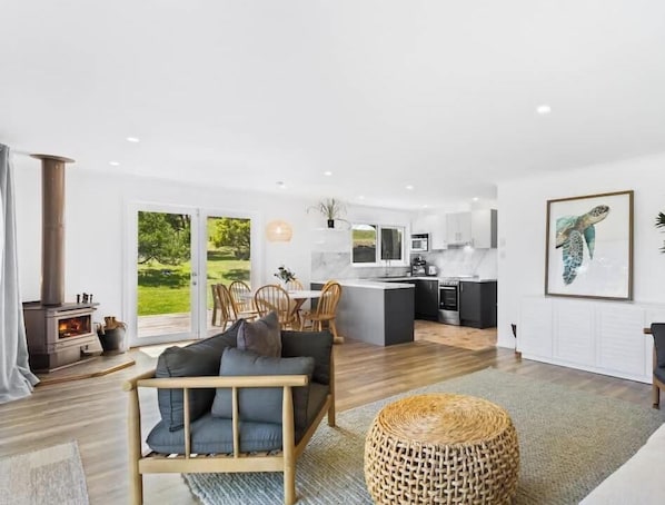 Een modern interieur met een bank, eethoek, keuken en grote ramen.