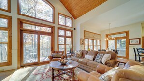 A spacious living room with large windows, a wooden ceiling, and a cozy seating area. - 5 Mi to Sapphire Valley Skiing: Serene Family Home (Sapphire)