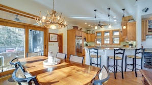 A spacious kitchen with wooden cabinets, a large island with bar stools, and a chandelier. - 5 Mi to Sapphire Valley Skiing: Serene Family Home (Sapphire)
