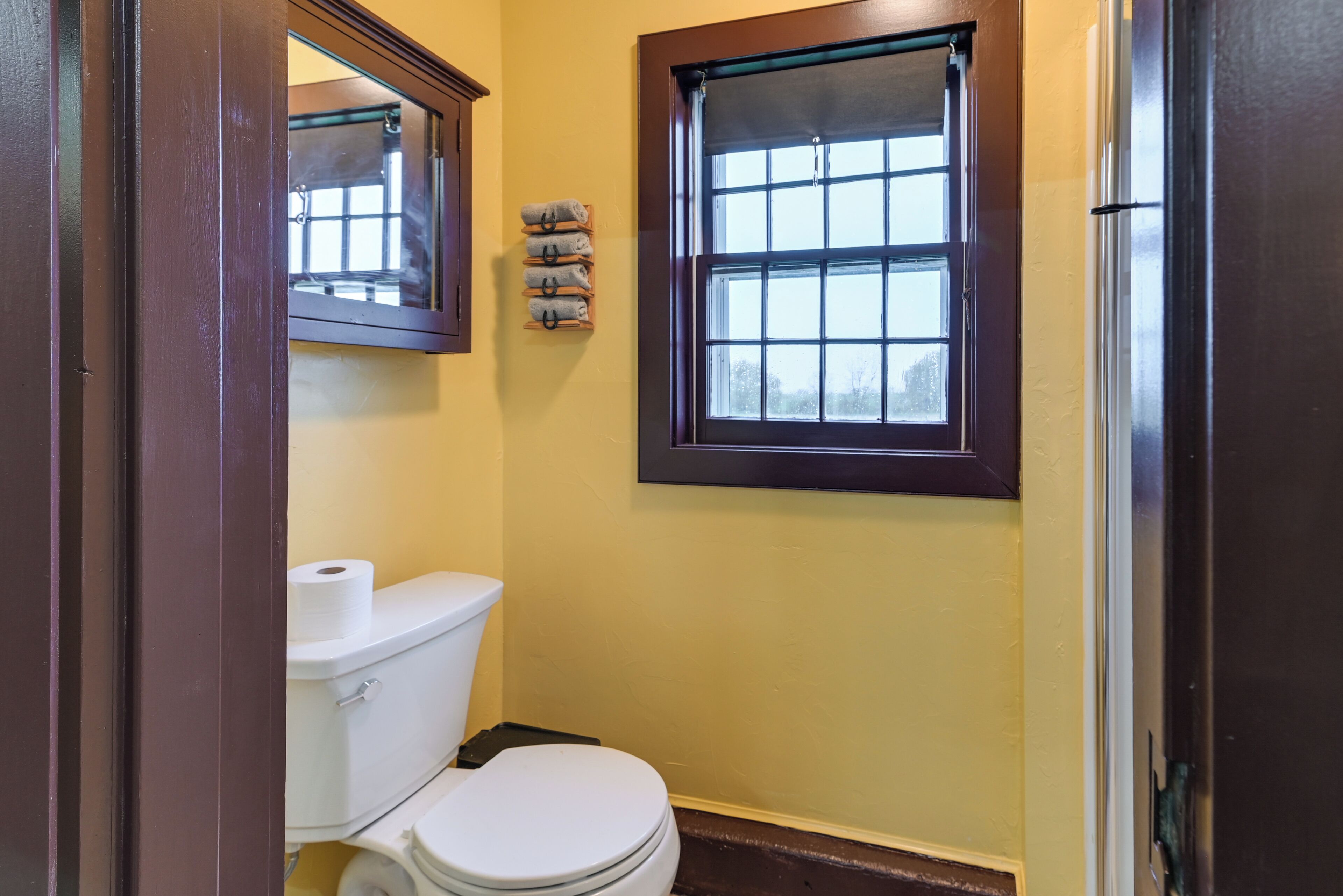 Une petite salle de bain avec des toilettes, une fenêtre et un porte-serviettes.
