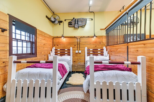 Una habitación con dos camas, una ventana, un ventilador y un perchero.