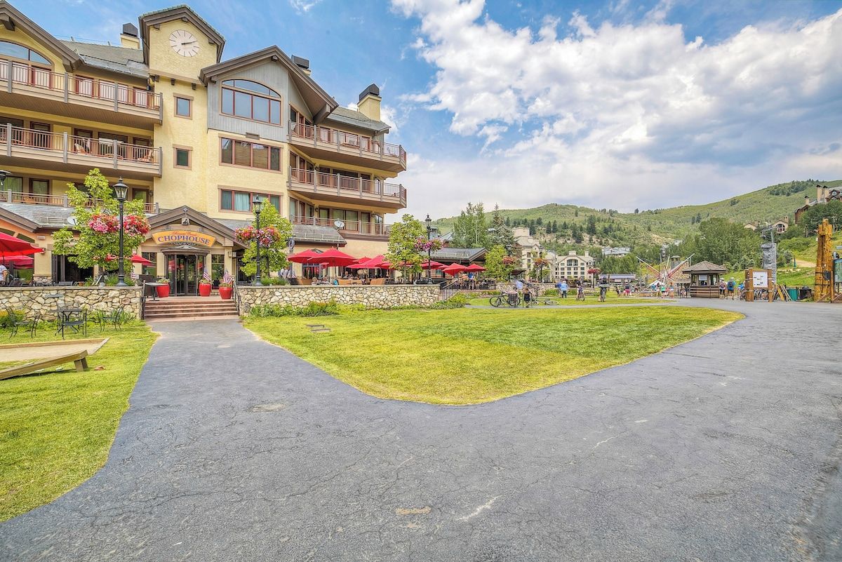 A hotel with a central courtyard, outdoor seating, and a view of a hilly landscape.