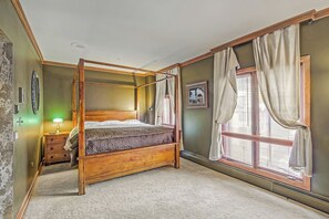 A four-poster bed with a wooden frame, a bedside table with a lamp, and a window with curtains. - Ski-In & Ski-Out Alpine Enchantment | Beaver Creek (Beaver Creek)