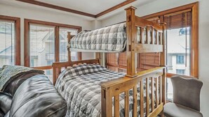 Une chambre avec un lit superposé doté d’une tête de lit en bois, un canapé et une chaise.